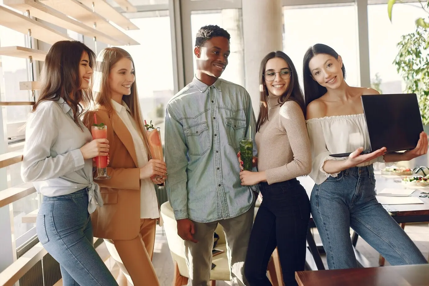 Люди разных национальностей стоят в кафе и пьют коктейли.